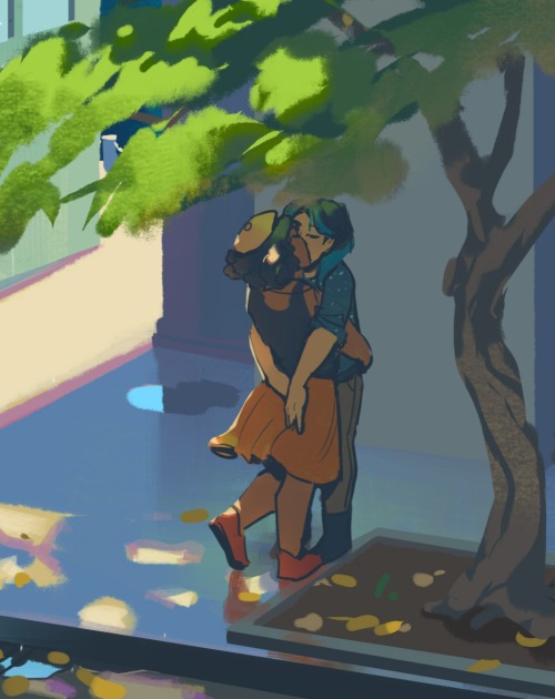 A close up shot of the two characters kissing under the tree in the first image in the post. One wears a yellow beret, a black tank top and an orange skirt. The other wears a deep blue shirt with sleeves rolled up and brown pants. Leaves are strewn around their feet, and a fragment of dappled light catches the first character's hair.