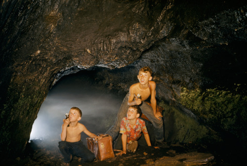 Boys exploring cave with flashlights look up in wonder near Harpers Ferry, West Virginia, March 1957