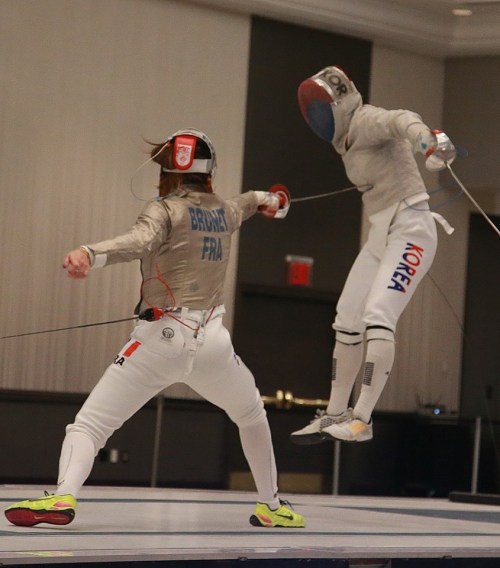 modernfencing: [ID: a sabre fencer leaping into the air as her opponent hits.] Manon Brunet (left) a