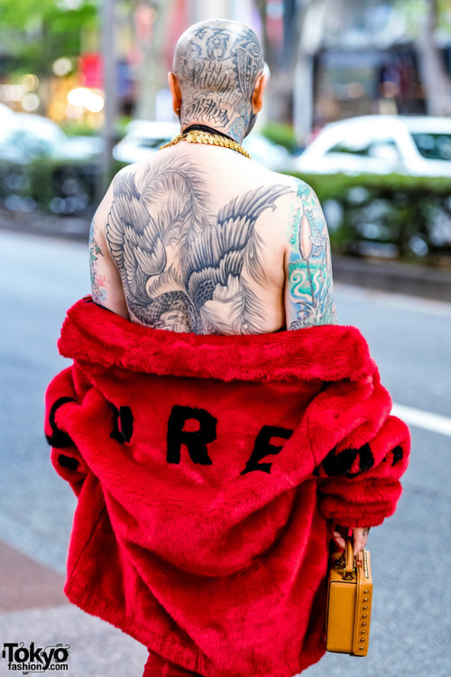 Fashion boutique owner Amy on the street in Harajuku wearing a red faux fur Supreme coat with a blac