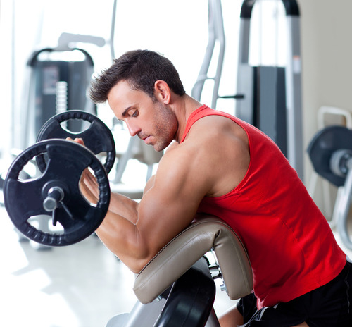 Homens maduros fazendo exercícios de supino inclinado com halteres na  academia