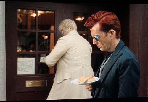 Screenshot: Crowley holding and looking down at the plate of cakes.