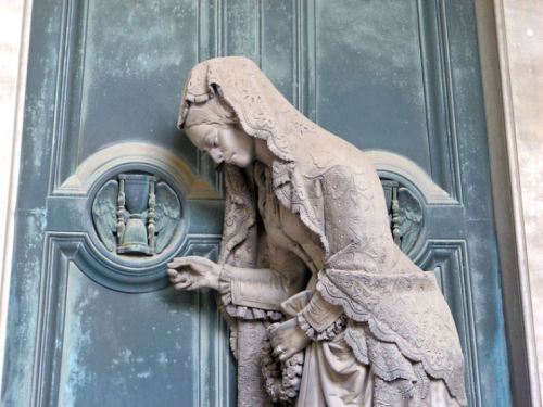 Sculpture of a woman knocking on a door from the tomb of Pietro Badaracco in Staglieno Cemetery by G