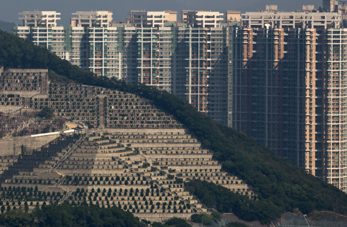 architectureofdoom: Graves cover a hillside next to apartment buildings at a cemetery in the Kowloon