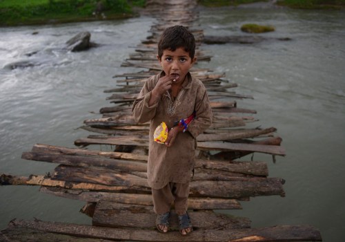 An Afghan refugee boy looks as he crosses a temporary wooden bridge at Jalala refugee camp in distri