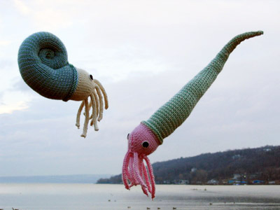 ghostwhalez:lakevida:nautiloid knitting patterns by beth skwarecki… wonders never cease
image: two knitted nautiloids on a cloudy beach. they look kind of like snails with tentacles. one has a coiled shell and the other one looks like it’s wearing a long, thin, pointy hat or as though the coiled shell has been unfurled. #Floating in the air  #Little snails floating in the air