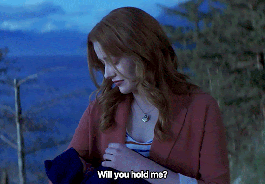 GIF FROM EPISODE 2X18 OF NANCY DREW. NANCY IS STANDING OUTSIDE AT THE BLUFFS, HOLDING AN INFANT IN HER ARMS. SHE LOOKS UP FROM THE BABY AND SAYS "WILL YOU HOLD ME?"