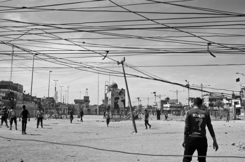 Moises Saman: IRAQ. Baghdad. March, 2014.Children play soccer next to concrete blast walls blocking 