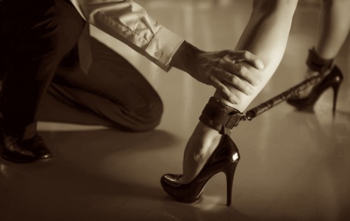 He places her naked, except for her high heels, in the center of the room, and binds her hands behind her back, her legs forced open wide so that she cannot hide, she cannot cover herself in any way. He gags her tightly so that she will not feel obligated