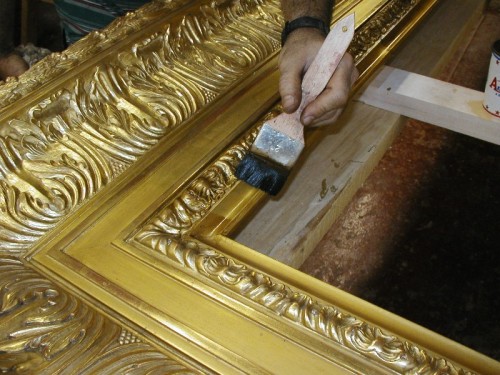 This reproduction of a 19th century frame was carved entirely by hand. The moulding is 12 inches wide and is finished in 22k gold leaf over yellow clay with red highlights. The pictures above show some of the steps during production.