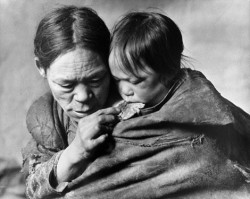 Richard Harrington, Padleimuit mother feeding her child a piece of caribou skin at starvation camp, 1950.