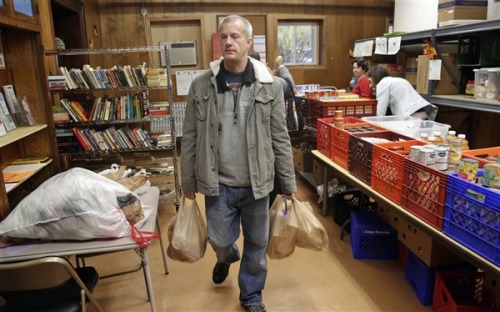 Larry Bossom, 41, who lost his job a few month ago, leaves the St. Ignatius food pantry with bags of