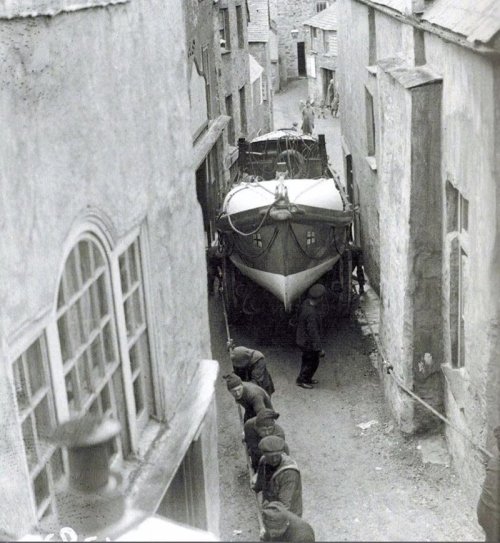 Sailors pull the boat through the narrow streets of the town of Port Isaac from the construction site for launching, England, 1928. Nudes & Noises  