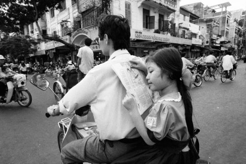 fotojournalismus:A father’s back makes a comfortable reading stand for this girl on her way to schoo