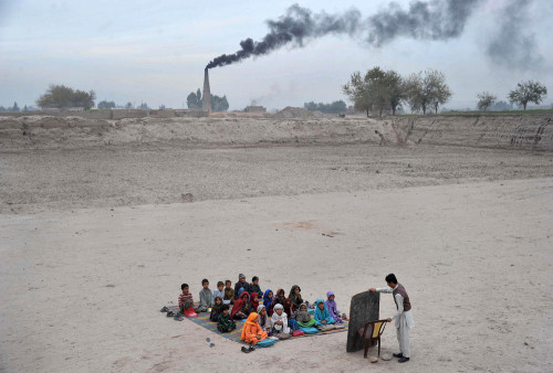Afghan schoolchildren take lessons in an open classroom at a refugee camp on the outskirts of Jalala
