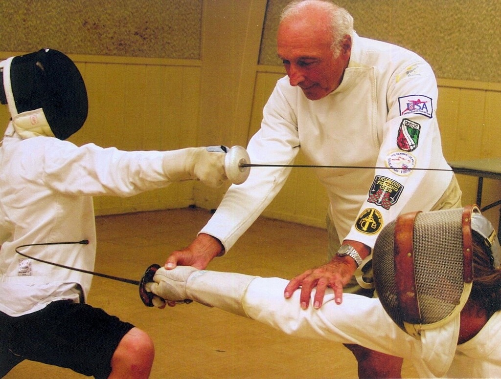 modernfencing:  [ID: two photos of a coach demonstrating a foil action to students,