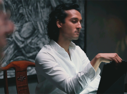Animated gif featuring Armand wearing a white shirt in the Dubai pentouse, picking up his iPad and getting up from the dining table where Daniel is seated