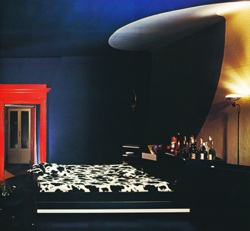 80sdeco:deep royal blue walls, red door trim, cow print bedspread, platform bed, ample baraqqindexLu