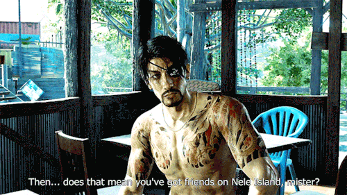 Majima is sitting at a table under a pagola surrounded by other tables and chairs. His hair is mused and he looks dirty, he's shirtless. His expression closes off as someone off screen speaks to him. Their subtitle reads: Then... does that mean you've got friends on Nele Island, mister?