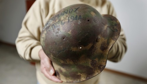 World War II veteran George Banky poses with a German rifle and helmet he acquired during his servic