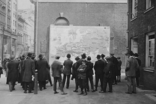 People on a street outside Independence Hall examining a new map of Europe shortly before the end of