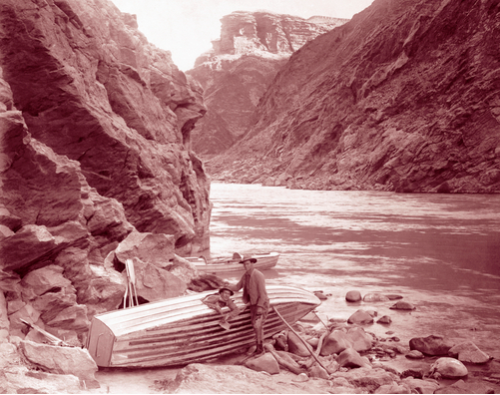 Two men stand next to their battered boat on the Colorado River