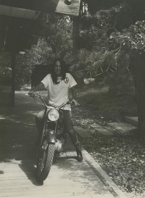 bobdylan-n-jonimitchell:Joan Baez riding a motorcycle with a peace sign on her t-shirt and cowboy bo