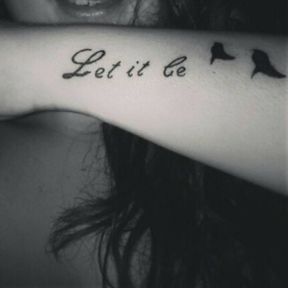 Tatuaje que dice “Let it be” (“Déjalo estar” en inglés) seguido de dos pájaros, en el antebrazo de Zaharenia.