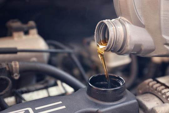 Mecânico completando o nível do óleo do motor do automóvel