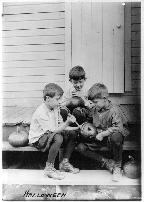onceuponatown:   Three boys on porch steps cutting faces in pumpkins for Halloween. 1917.
