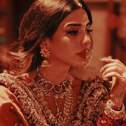 a punjabi bride dressed in orange and gold finery with lots of elegant jewellery