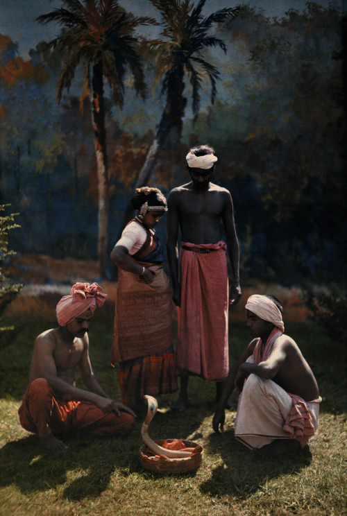 A group of people gather round and watch a snake charmer at work in India, 1923.Photograph by Hans H