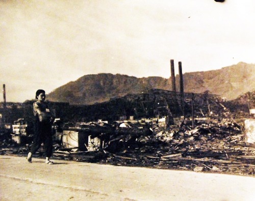 historicaltimes:A woman walks past the Mitsubishi Steel and Arms Works that was destroyed by the ato