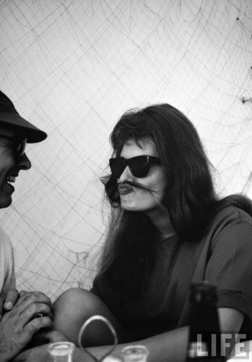 Alfred Eisenstaedt - Movie producer Carlo Ponti laughing at his actress wife Sophia Loren who has put a strand of hair across her mouth like a mustache in an off-beat restaurant, Italy, 1961.