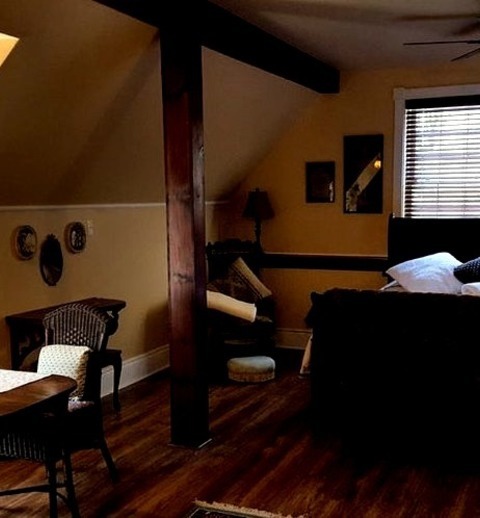 Loft-Style Bedroom TorontoAn Expansive Image Of A Cottage Loft Bedroom With Beige Walls, A Corner Fireplace,