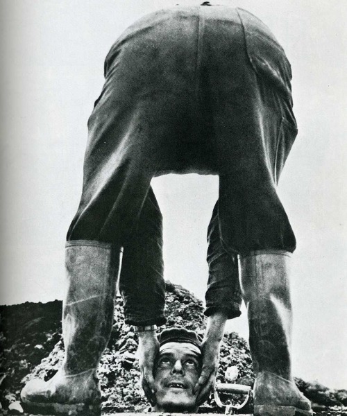 A workman in Copenhagen creates the illusion that he is reaching for his fallen head, with the assistance of a cohort and the hole they are digging.