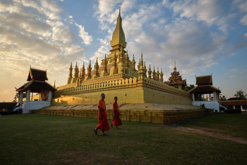 That Luang by fredMin Two Buddhist Monks are passing in front of the Pha That Luang in Vientiane , L