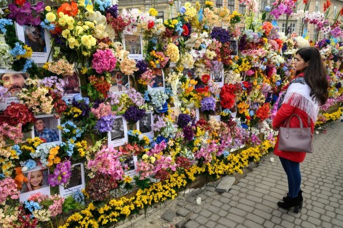 A woman looks at a floral memorial wall for Ukrainian civilians killed during the Russian invasion, 