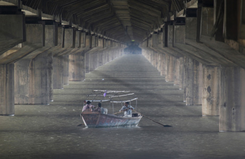 A man rows a boat in the flooded waters of river Ganges under a bridge in the northern Indian city o