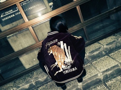 N Ryoka wearing a Japanese souvenir jacket on the street.