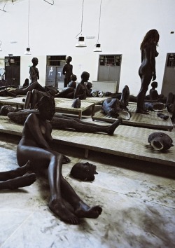 shoulderblades:  vb66, vanessa beecroft, 2010 the work consists of a group of sculptures taken from casts of real people mixed among a vast group of girls with black make-up. the girls hide in the dark space and are confused with the sculptures.  