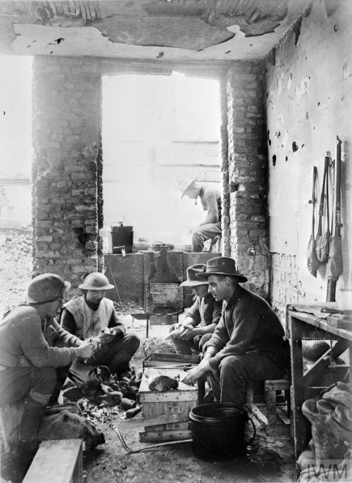 scrapironflotilla:Australian troops prepare a meal in their billet among the ruins of a house near Y