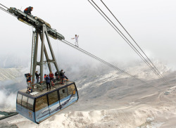 sixpenceee:Germany: High above Bavaria’s Zugspitze mountain, Swiss tightrope artist Freddy Nock nears the end of his 2011 quest to walk a two-inch-thick, 3,264-foot-long cable without a balancing pole. He succeeded, as photographers looked on. (Source)