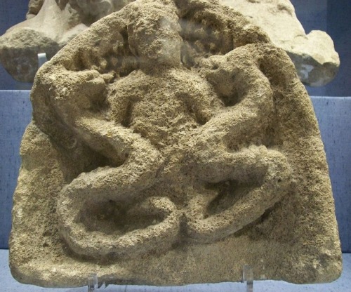 Iron Age carving of the horned god Cernunnos, grasping two serpentswho are eating either fruit or co