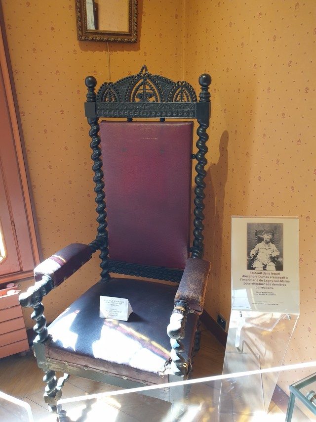 a photo of a very used antique chair next to a picture of an older Dumas in that very chair 