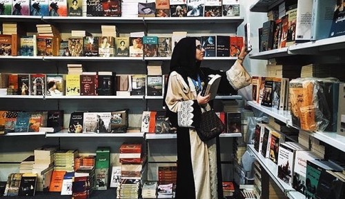 everydaysaudi: Woman is picking a book from a book corner in the international book exhibition in Ri