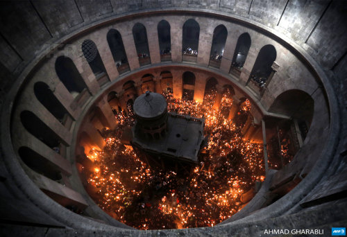 afp-photo:JERUSALEM : Christian Orthodox worshipers hold up candles lit from the “Holy Fire” as thou