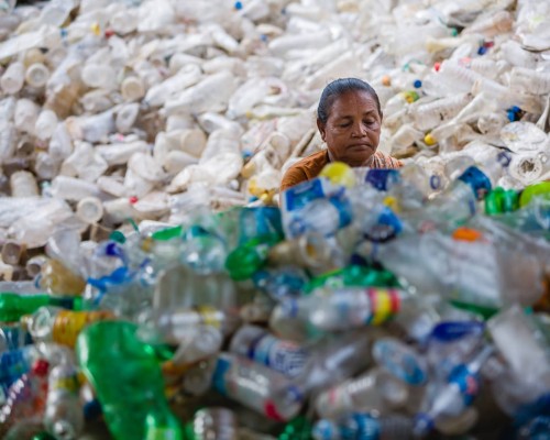 Nearly hidden in a sea of plastic, a resident of a slum in...