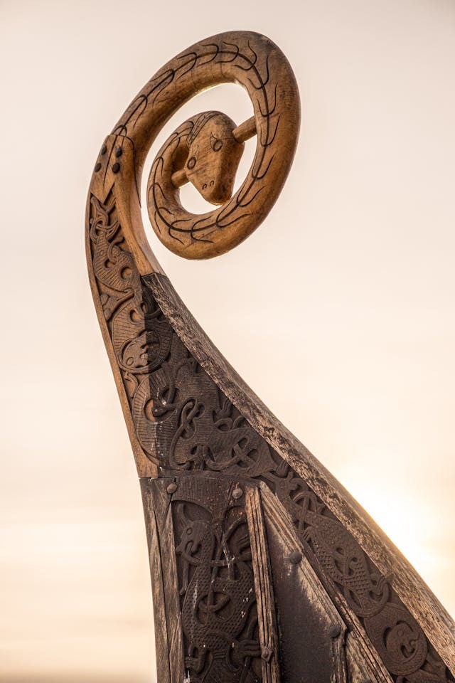 Photo of the carved prow of a Viking boat. The curlicue is in the form of a snake. There is are snakes and/or dragons visible in the other carvings.