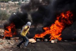 soldiers-of-war: PALESTINIAN TERRITORIES. West Bank. Near Nablus. Kfar Qaddum. November 11, 2016. A Palestinian protester uses a slingshot to hurl stones towards Israeli security forces during clashes following a demonstration against the expropriation